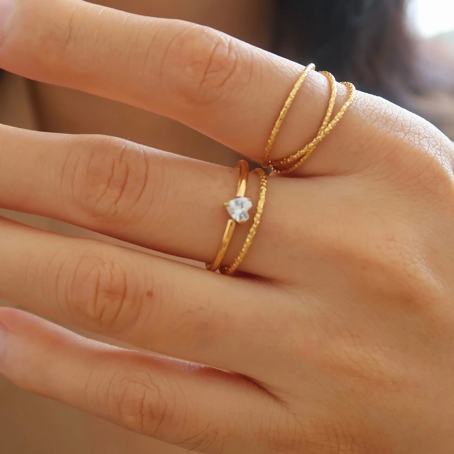Golden heart-shaped stainless steel ring with electroplated finish shown in UK sizes 5-8