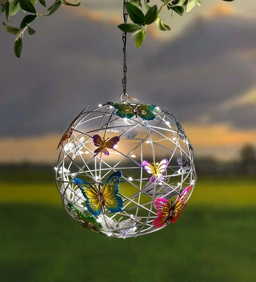 White outdoor solar ball light with random colour butterfly decorations on a garden lawn