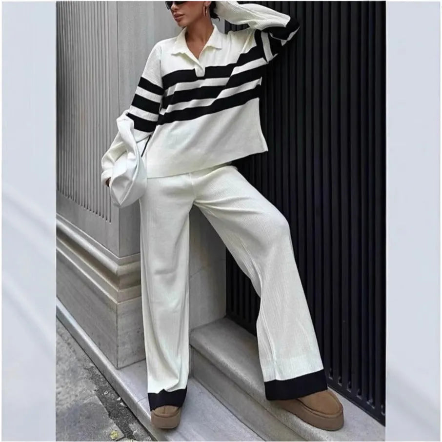 Women's black and white striped knitted two-piece set with polo collar top and straight-leg trousers laid flat.