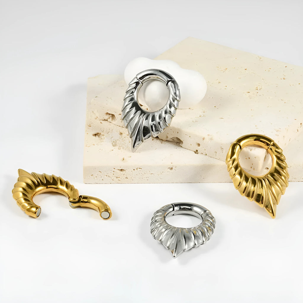 A single stainless steel teardrop-shaped ear extender for stretched lobes, showing a totem pattern on its face.