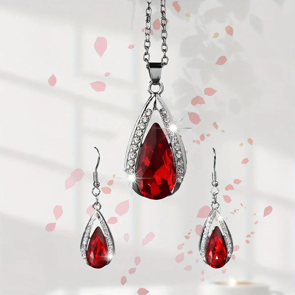 Black and red teardrop-shaped glass pendant necklace and matching earrings set laid flat.