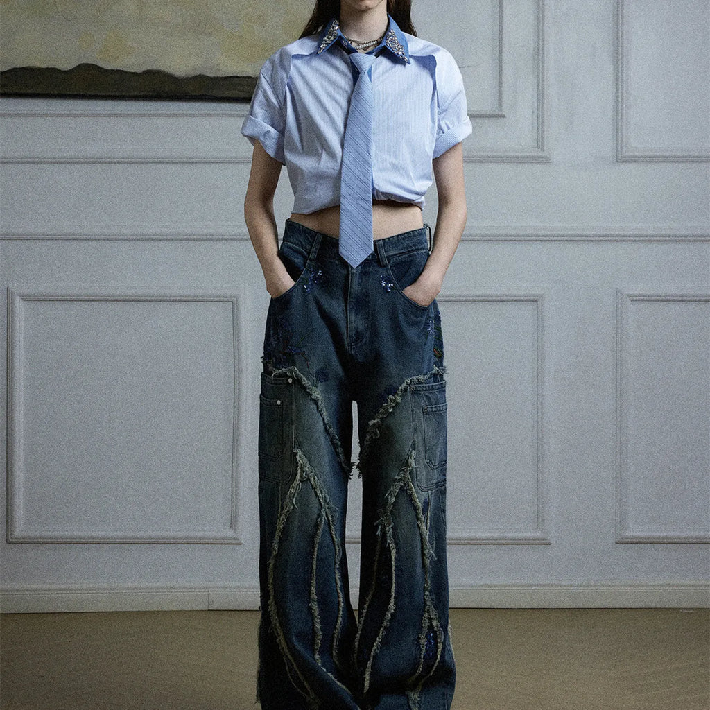 Man wearing a blue loose fit shirt with patchwork stripes, a diamond tie detail, and a flip collar.
