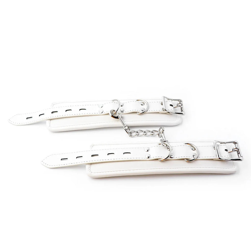 White PU sponge bondage set showing handcuffs, footcuffs, ankle bracelet, and neck scarf on a dark background.