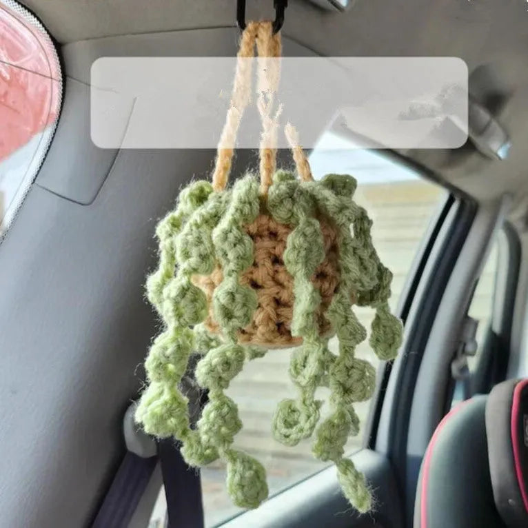 Green and white crocheted wool car plant decoration with a white hanging rope.