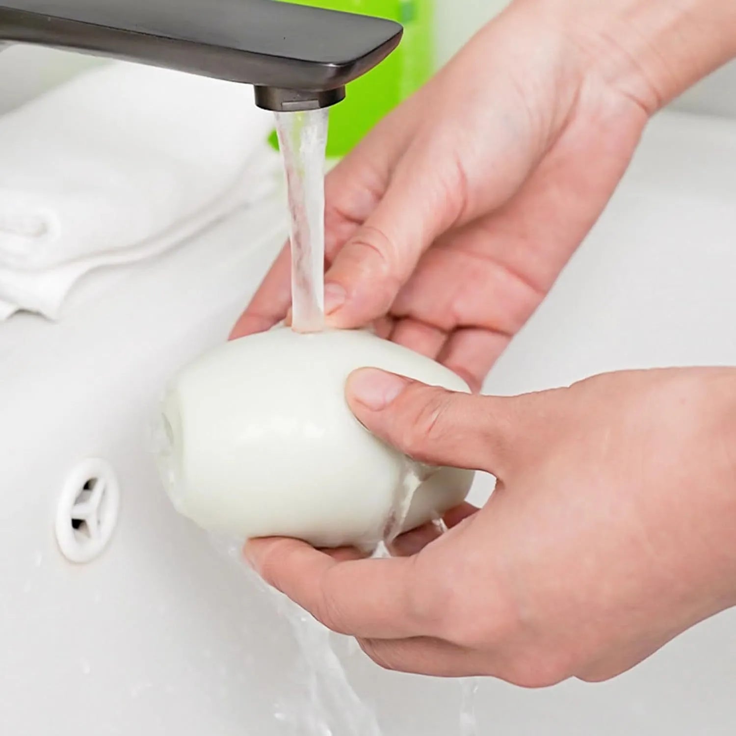 Green and white washable gel lint roller ball for pet hair removal on fabric.
