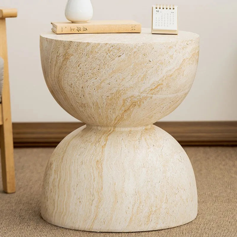 Modern hourglass-shaped tea table in imitation cave stone finish placed beside a sofa in a living room
