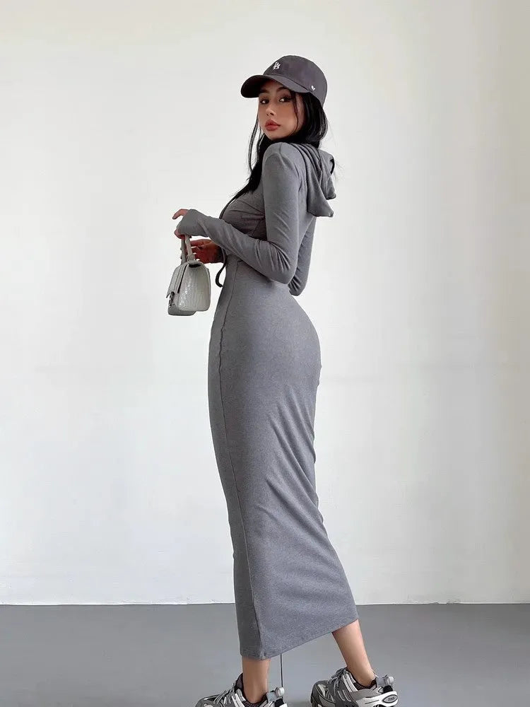 A woman modelling a grey hooded long-sleeve sheath dress with a high waist.