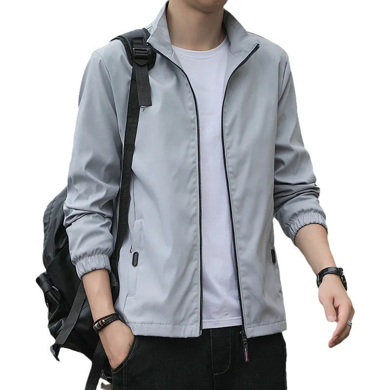 Man wearing a loose-fit grey lapel jacket, a Korean-style autumn casual outerwear piece with zipper pockets.