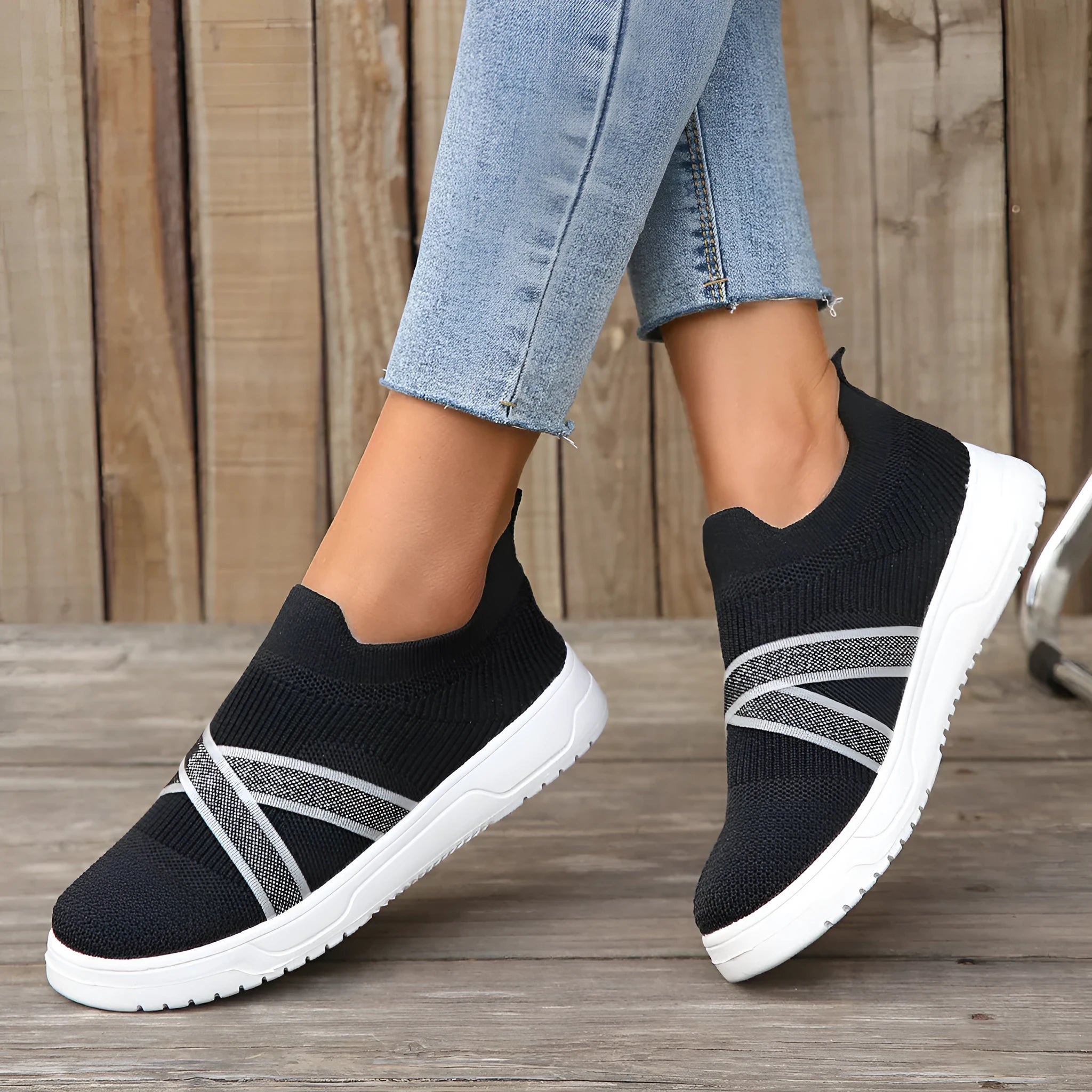 Black women's flat casual shoes with flyknit mesh upper and tassel detail on a flat rubber sole.