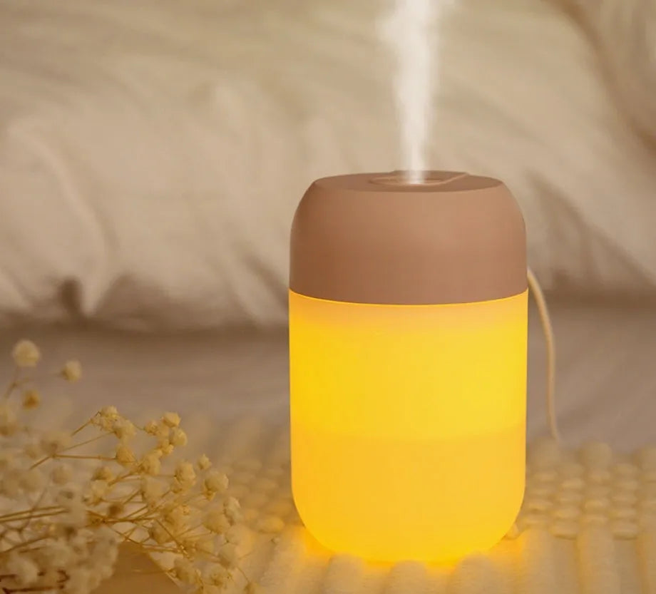 Small white cylindrical USB humidifier with aromatherapy diffuser on a wooden surface.