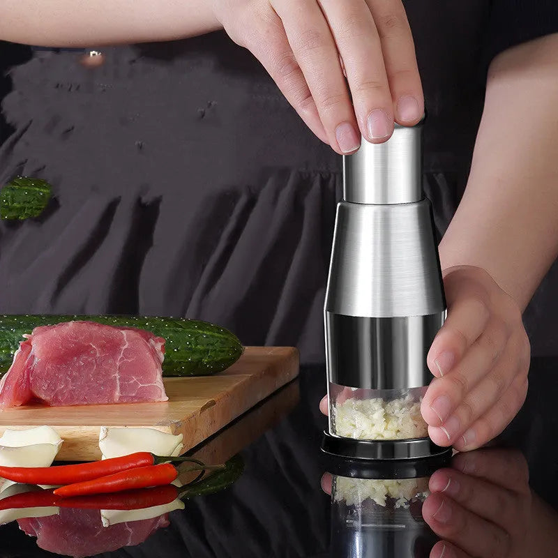 Manual garlic crusher and onion chopper in black with stainless steel blades on a kitchen counter