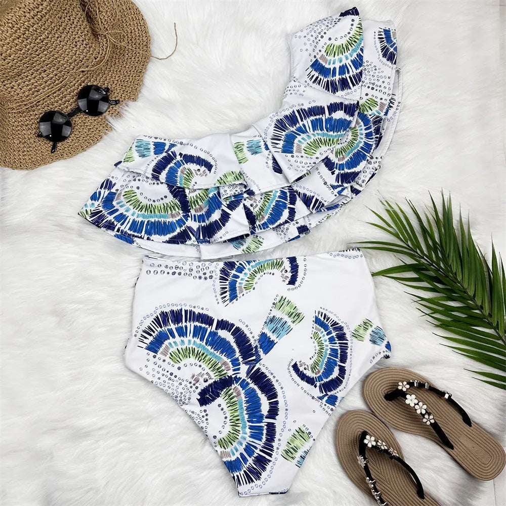 White women's one-shoulder bikini with large lotus leaf detail and split-leg design.