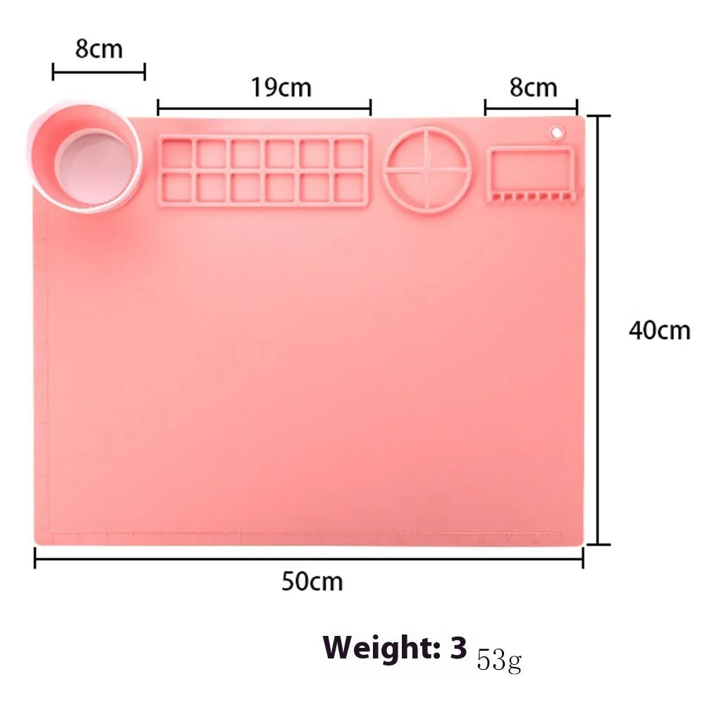 Light blue silicone painting mat with two round bowls, placed on a wooden table with paint brushes