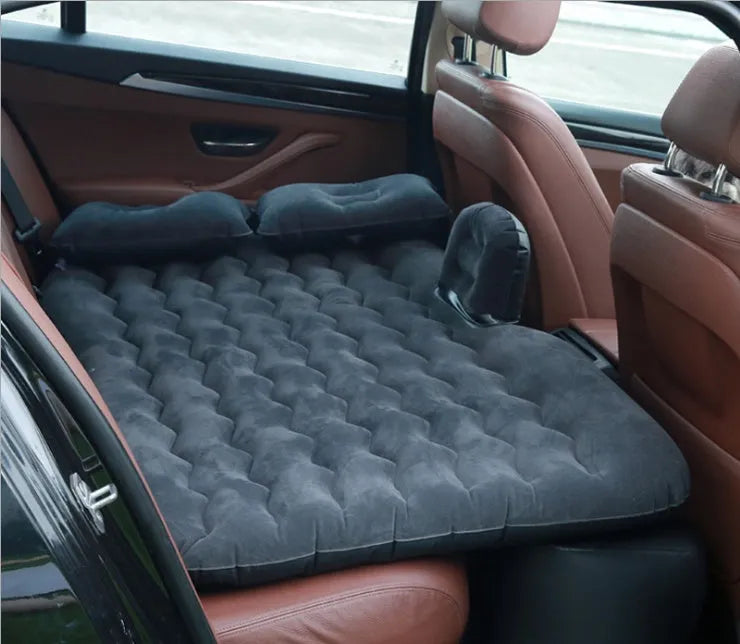 Black car inflatable bed with two pillows, shown inflated in a vehicle's rear compartment.