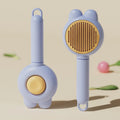 Self-cleaning cat brush with release button showing stainless steel teeth with rubber tips