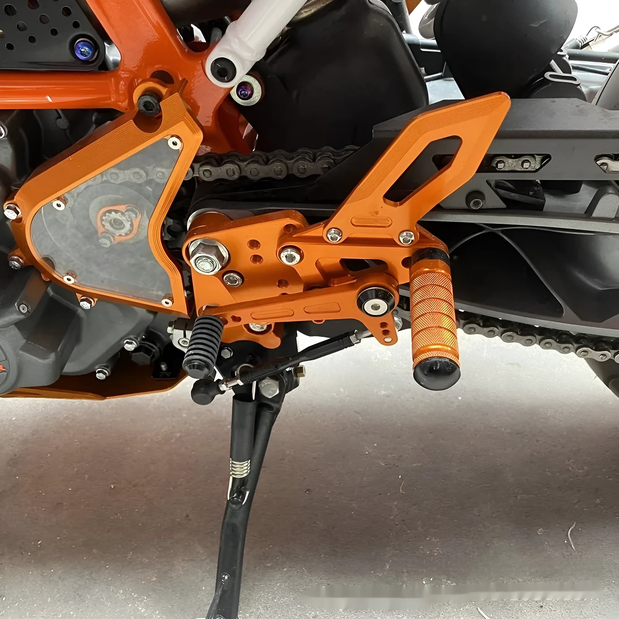KTM DUKE motorcycle raised rear shift pedal support bracket assembly in black and orange