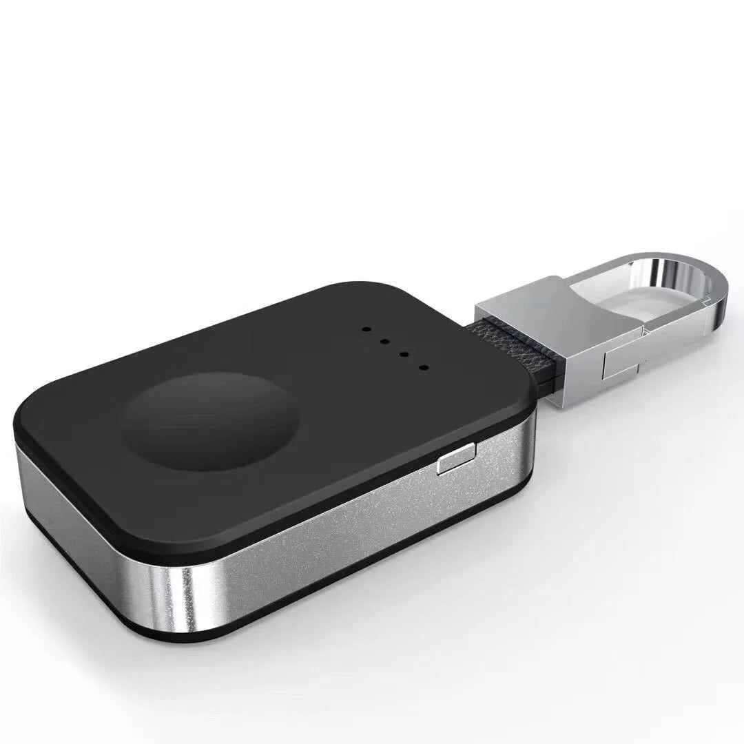 Black Apple Watch keychain power bank with wireless charging pad next to an Apple Watch.