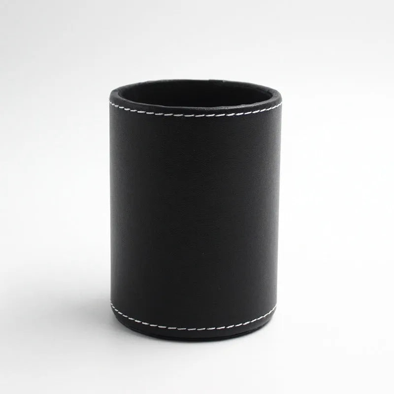 Small round black leather pen holder on a desk.