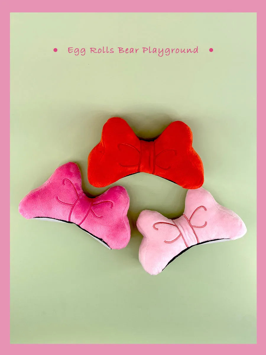 Soft plush bow tie decoration for helmets in red, peach pink, and rose pink on a motorcycle helmet.