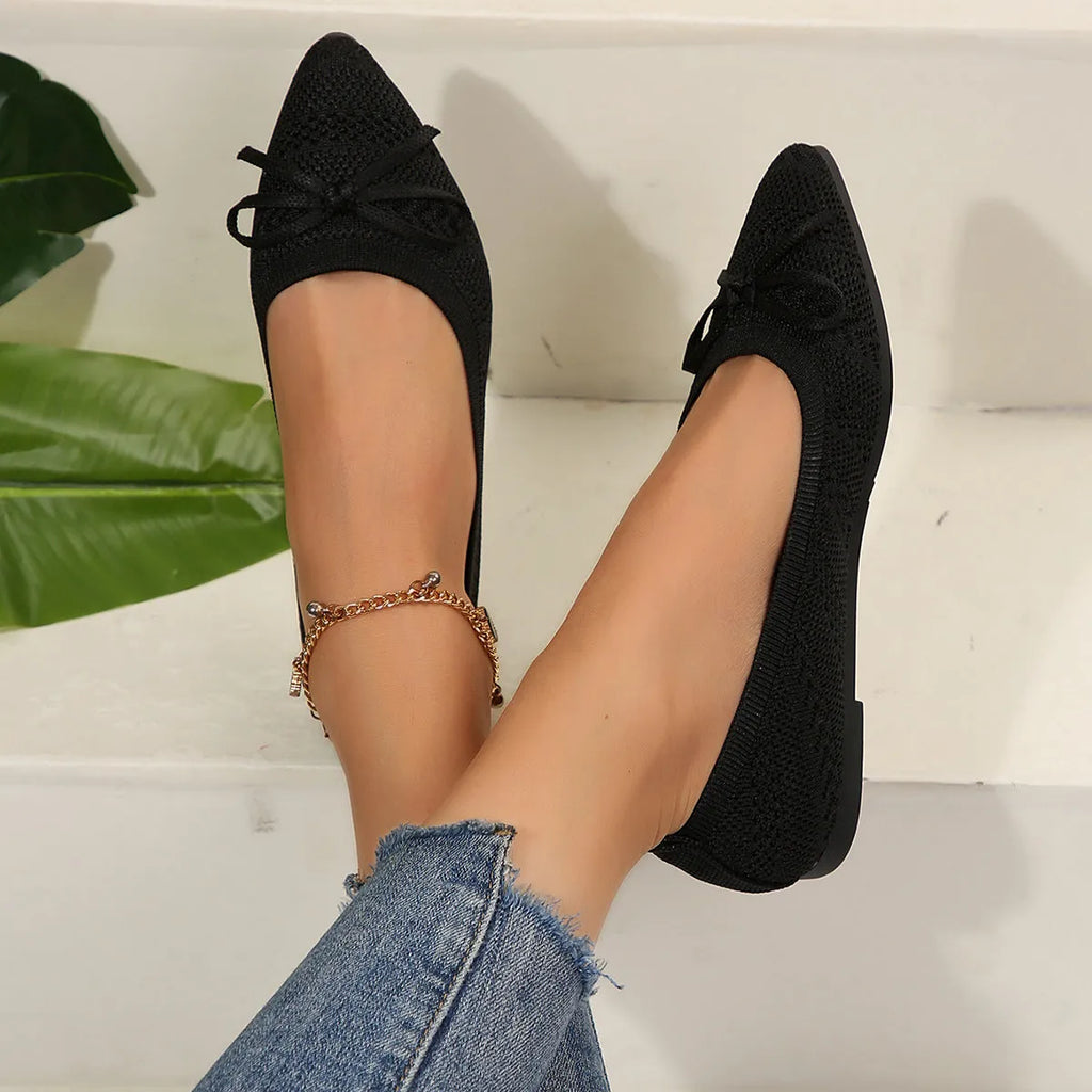 Women's knitted flat shoes with a bow detail and pointed toe in various colours on a plain background.