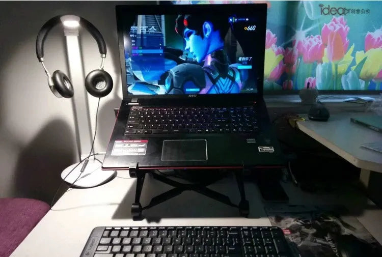 Black foldable enhanced nylon laptop stand shown open next to its portable carry bag.