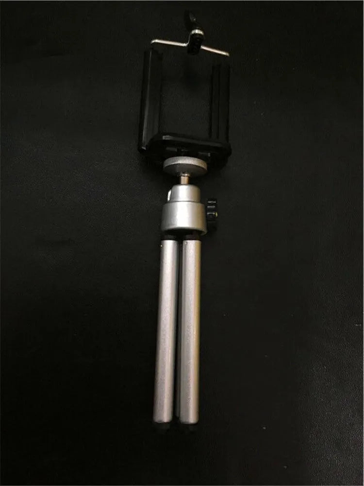 Black aluminium desktop phone holder with a two-section bracket on a wooden desk.