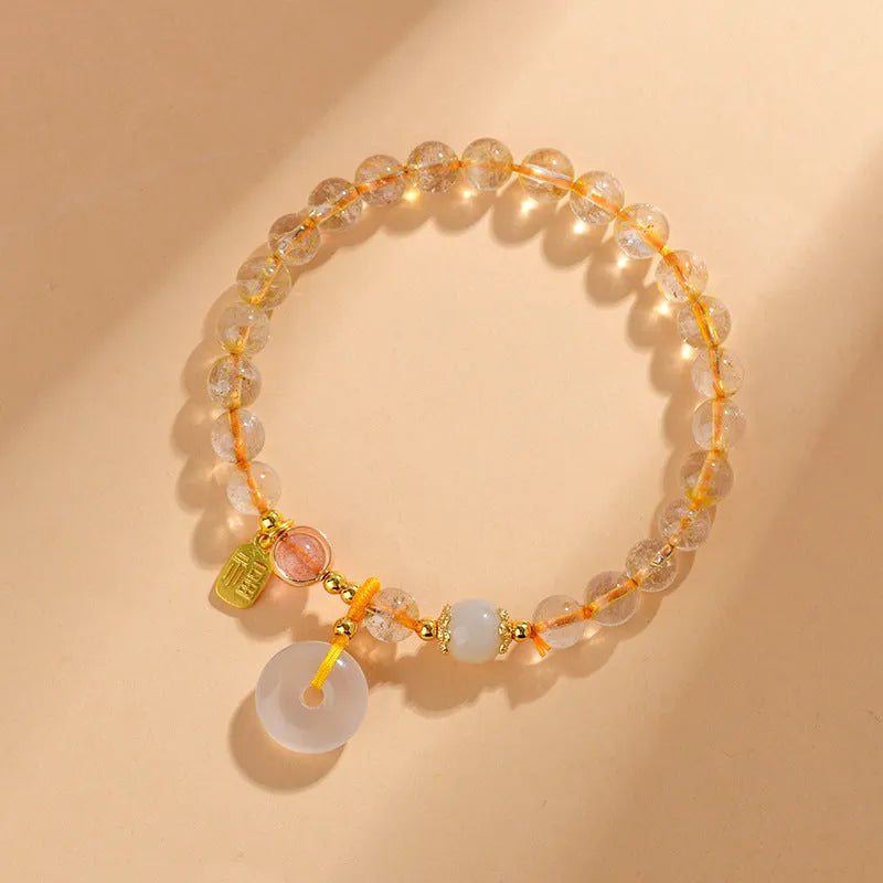 Gold rutilated quartz bracelet with a peace buckle pendant and geometric safety clasp.