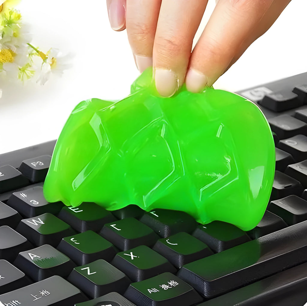 Blue magic cleaning gel putty being pressed onto a laptop keyboard to remove dust.
