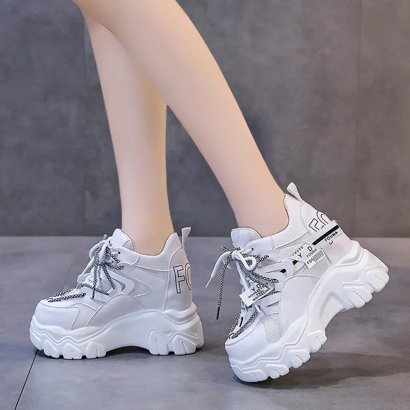 White women's low-top platform sports shoes with a cross-strap over a shallow-cut collar and a thick rubber sole.