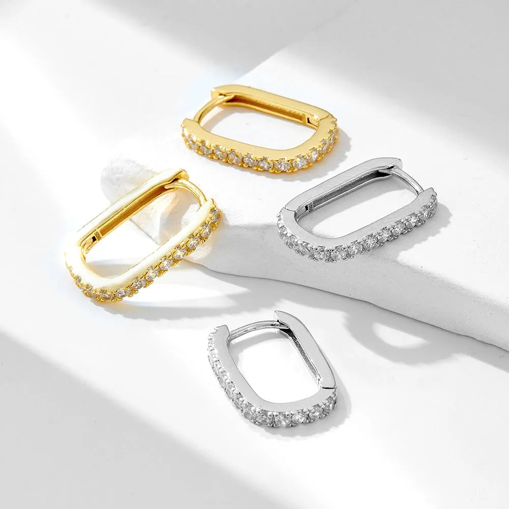 A pair of oval geometric sterling silver ear clips with zircon stones in white or yellow colour.