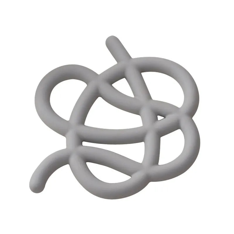 Irregular-shaped ceramic heatproof mat in a solid colour on a wooden table, protecting it from a hot pan.