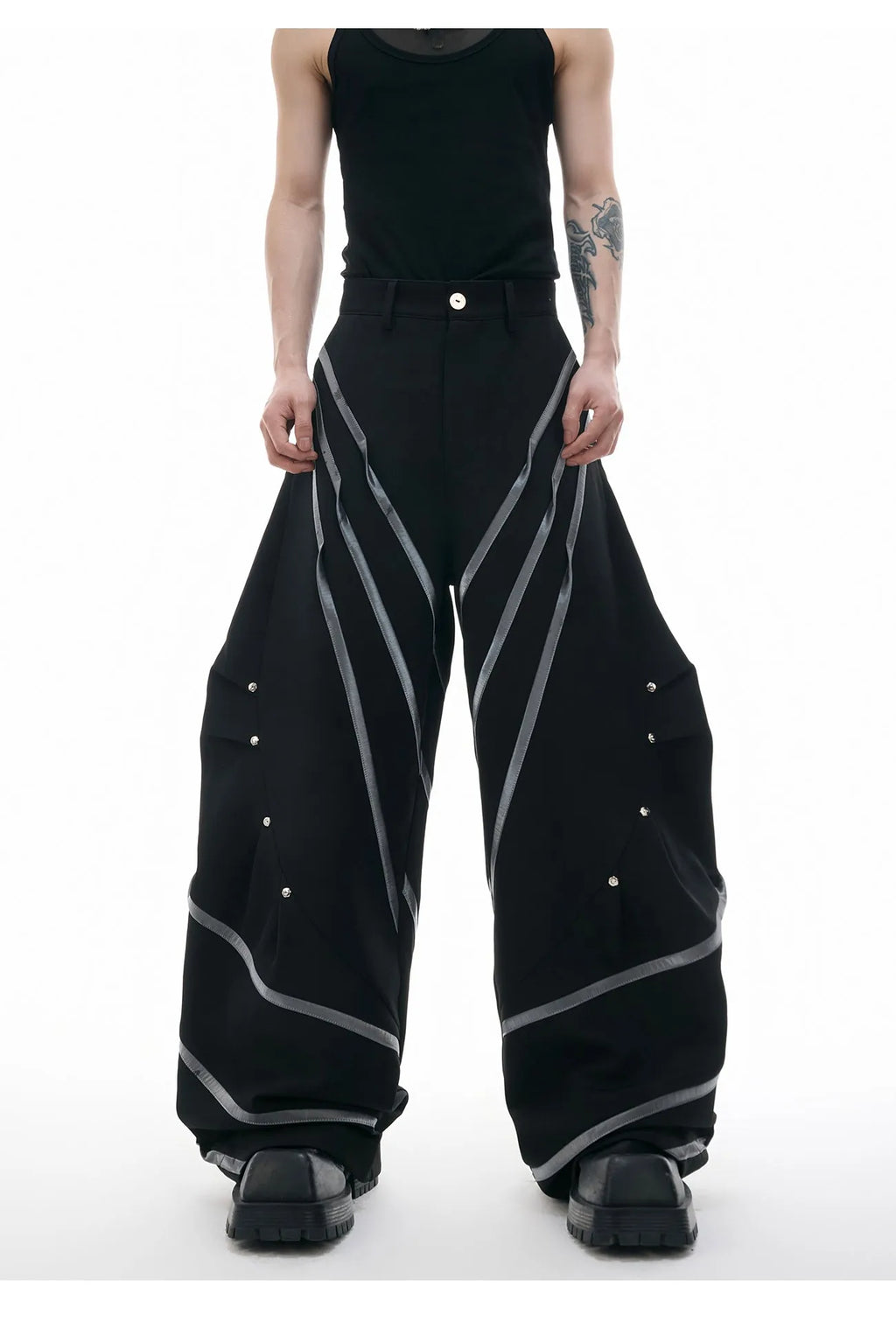 Men's black polyester trousers with three-dimensional cut and metal striped rivets on the pleats.