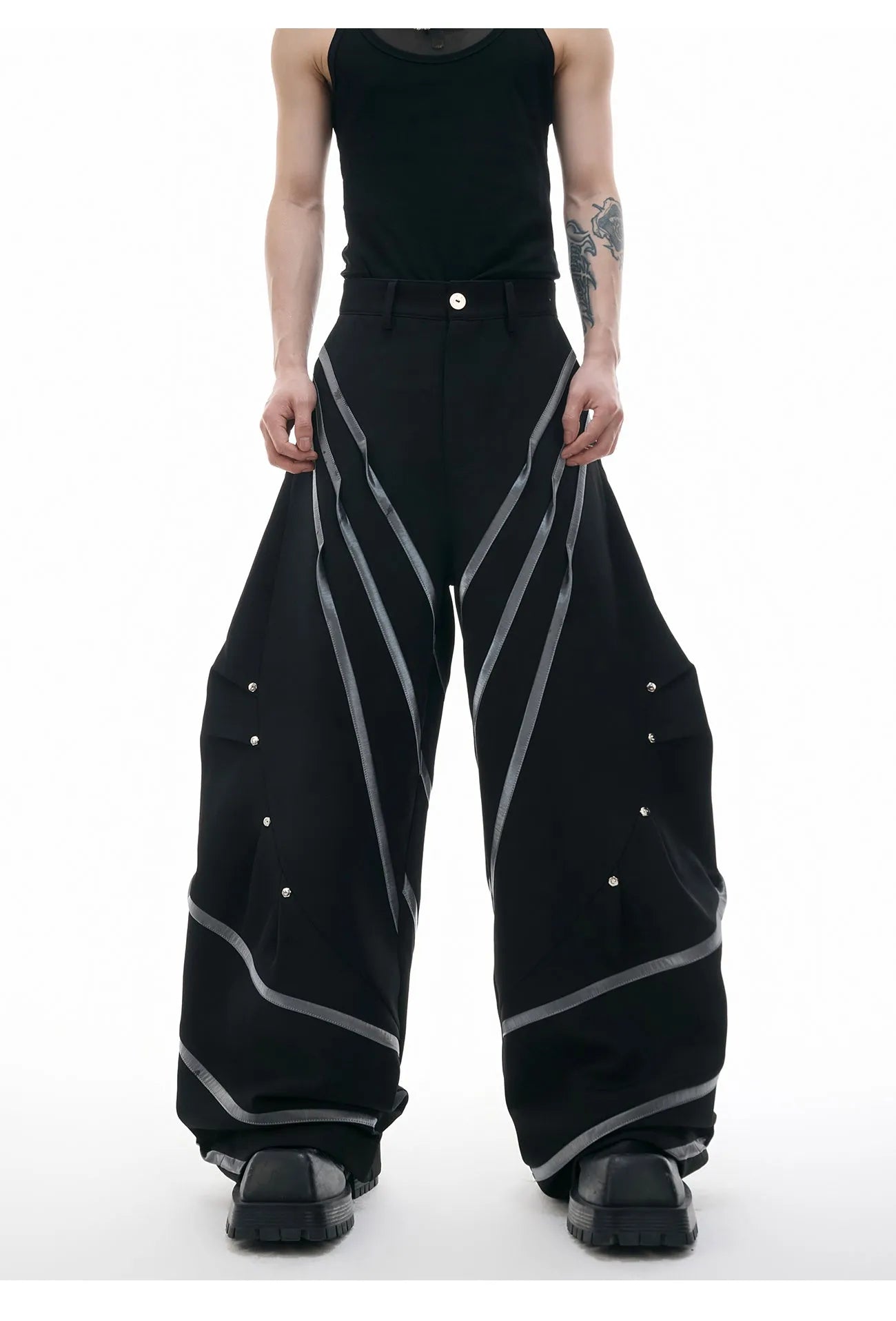 Men's black polyester trousers with three-dimensional cut and metal striped rivets on the pleats.