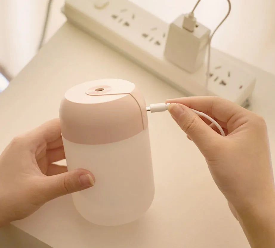 Small white cylindrical USB humidifier with aromatherapy diffuser on a wooden surface.