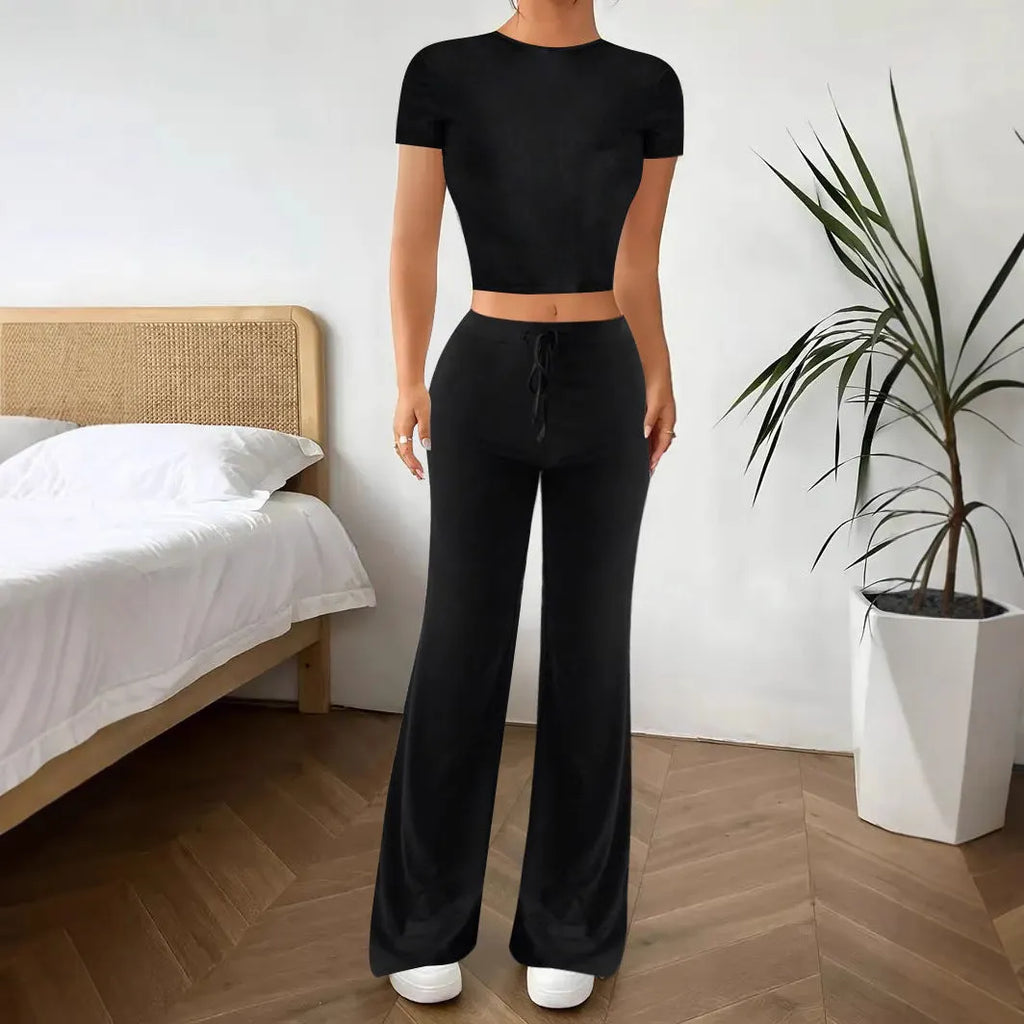 A woman's black high-waist trousers and matching short-sleeve T-shirt co-ord set laid flat.