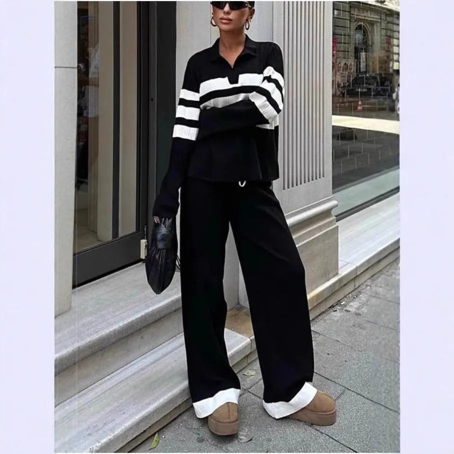Women's black and white striped knitted two-piece set with polo collar top and straight-leg trousers laid flat.