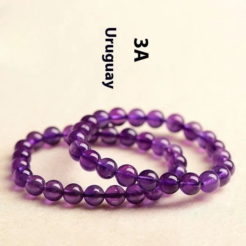 Loose polished amethyst beads on an elastic cord, forming a natural Uruguay crystal bracelet in violet shades.