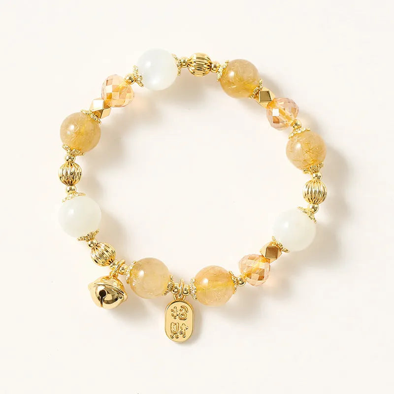 Gold rutilated quartz crystal bracelet with a ringing bell charm in Korean style.