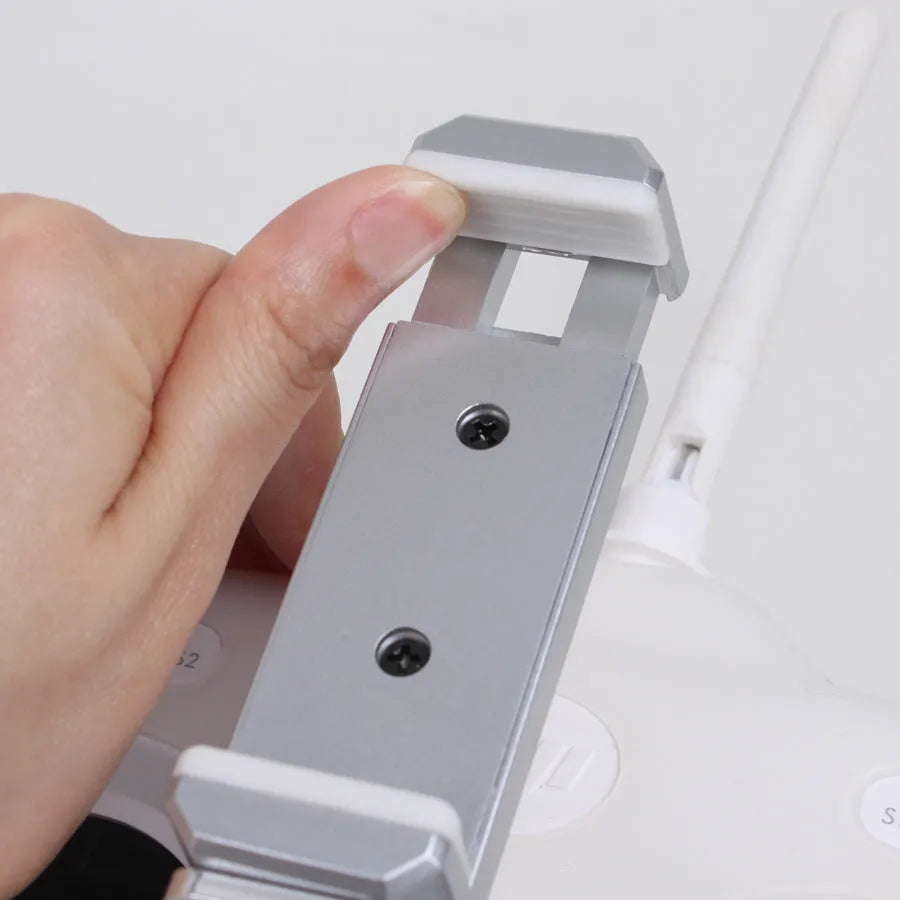 Silver mobile phone holder tongs with a remote control lanyard, a car accessory for elderly users.