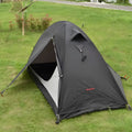 Single person orange double-layer hiking tent pitched in a field with aluminium poles visible.