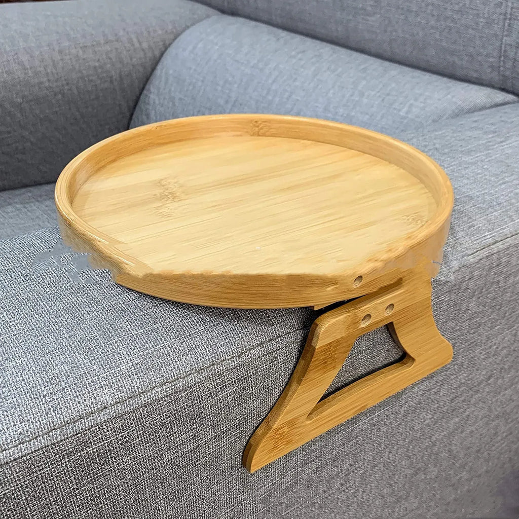 Wooden clip-on sofa tray table with carved surface in bamboo colour, attached to armrest holding snacks and remote