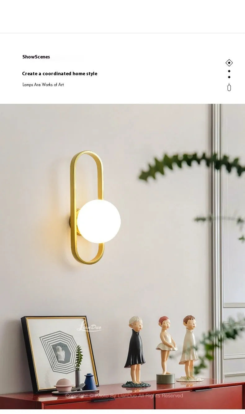 Minimalist circular wall lamp with glass shade on iron arm, in black finish, mounted beside a bed.