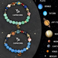 Set of twelve natural stone beaded bracelets on a table, each with different beads representing zodiac signs.