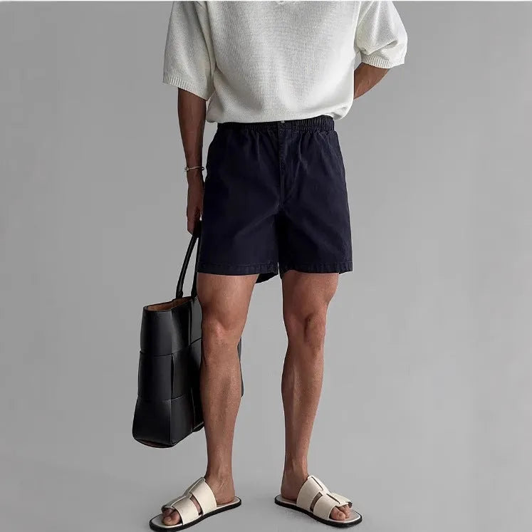 Man's loose-fit cotton sports shorts in black, showing elastic waistband with drawstring.