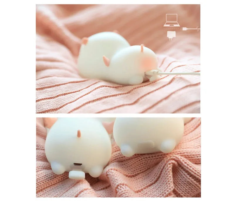 Pink silicone night light in the shape of a sleeping pig on a table.