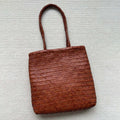 Brown handmade woven cowhide leather tote bag with a three-dimensional outer pocket.