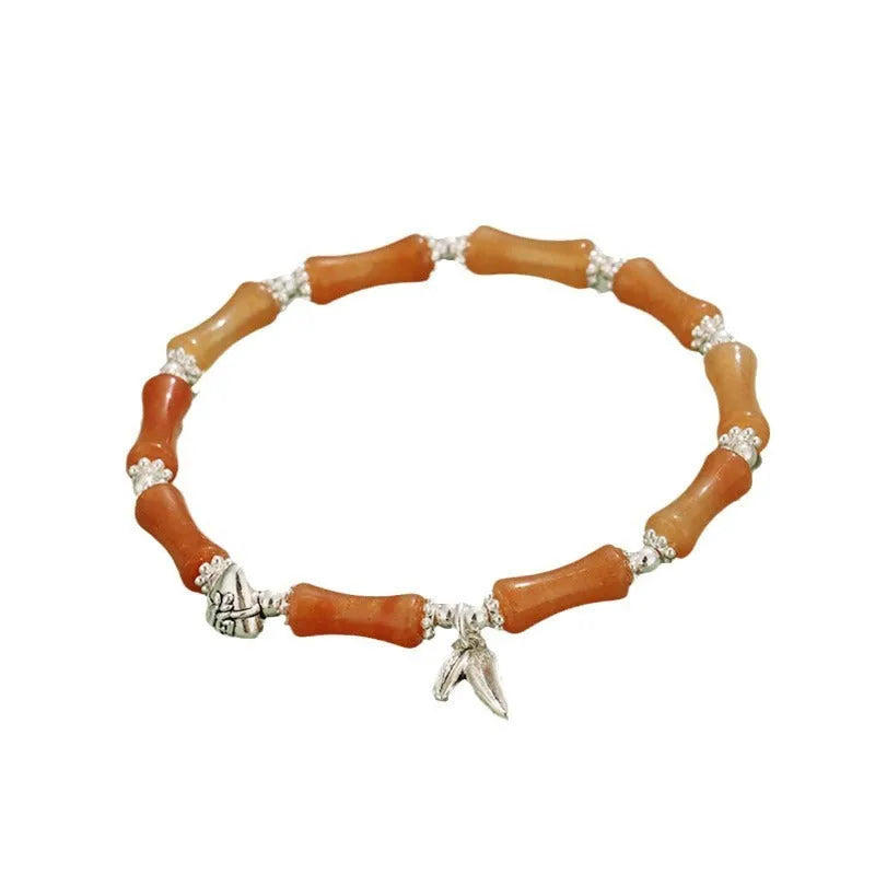 Women's green aventurine crystal bracelet with bamboo, strawberry quartz, and jade beads on wrist.