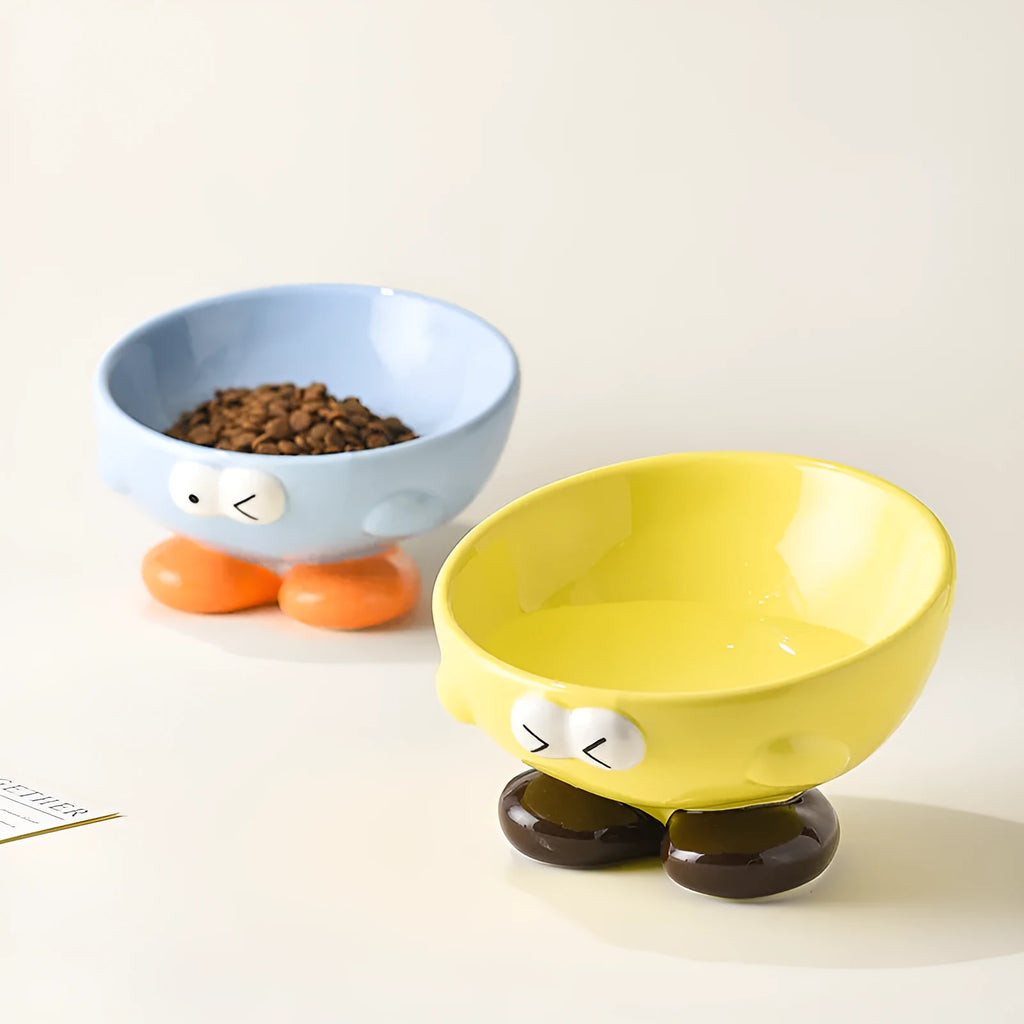 Blue ceramic pet bowl with tall, angled sides and a cute face design for cat or small dog feeding.