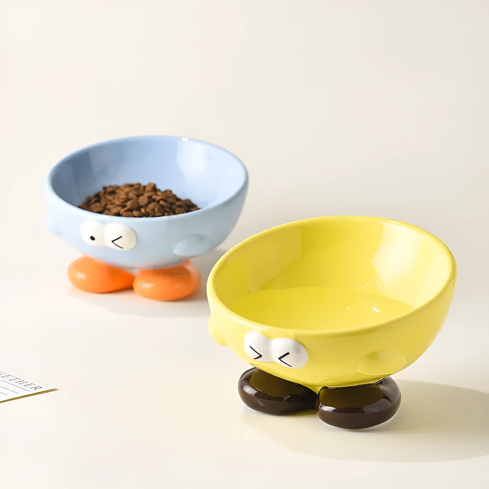 Blue ceramic pet bowl with tall, angled sides and a cute face design for cat or small dog feeding.