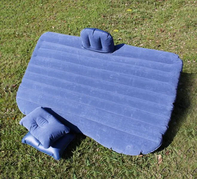 Inflatable car bed with flocked surface and two pillows, laid out in a vehicle.